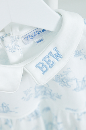 Close-up of a white baby outfit featuring a delicate Peter Pan collar