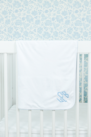 White baby blanket draped over a crib rail