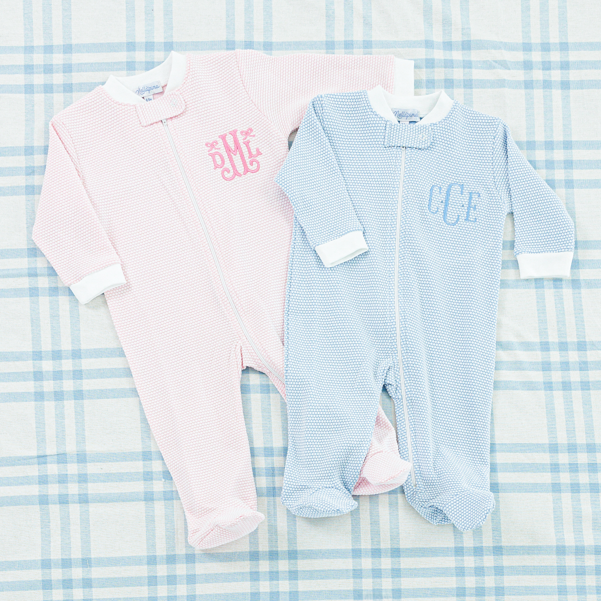 Two baby onesies, one in light blue and the other in soft pink.