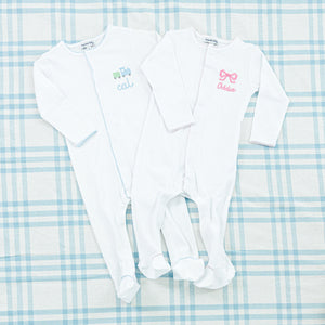 Two personalized baby onesies both in soft white fabric.