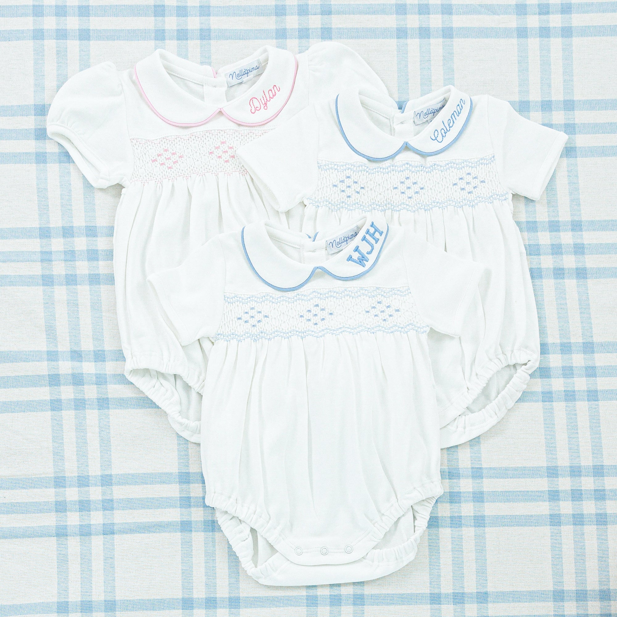 Two white smocked onesies in 2 different colors: pink and blue.