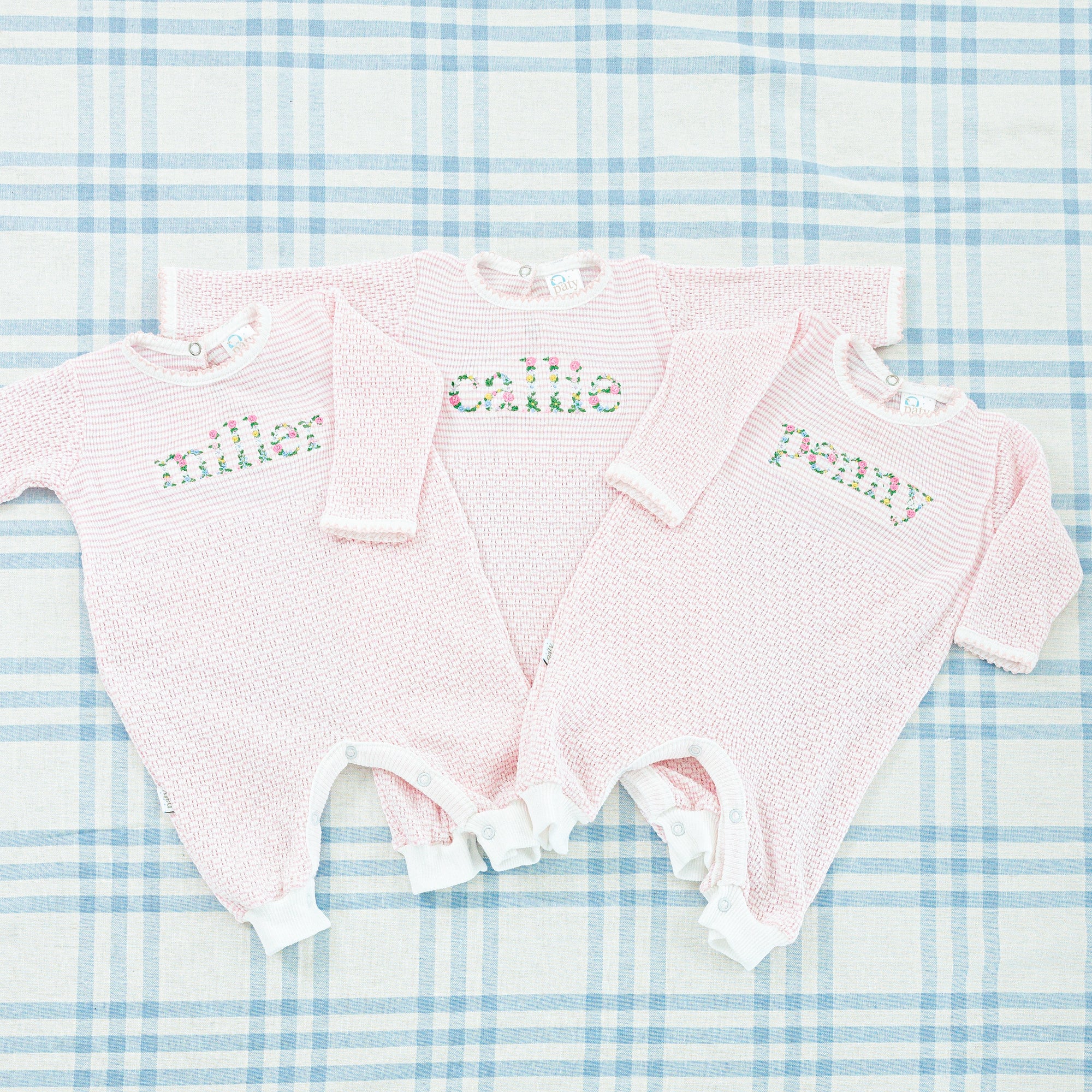 A pink baby onesie featuring long sleeves and a full-length design 