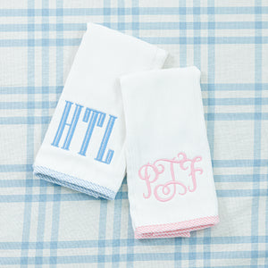 Two soft white towel with embroidered blue and pink initials.