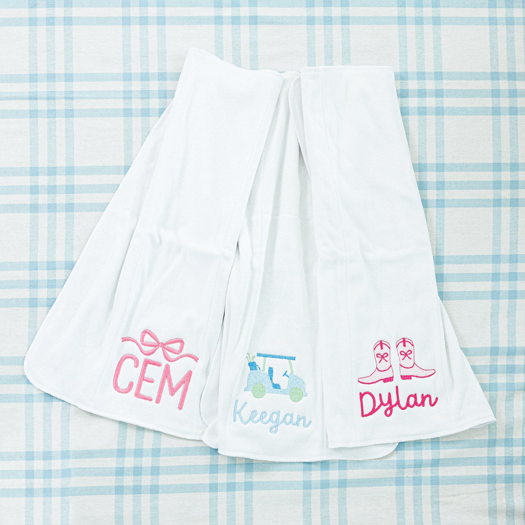 Two white personalized towels, one with a blue saddle design and the other with a pink bow design.