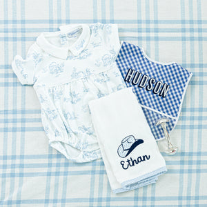 A personalized baby gift set and 'Hayes' embroidered on the collar, a blue gingham bib with 'Hudson' embroidered.