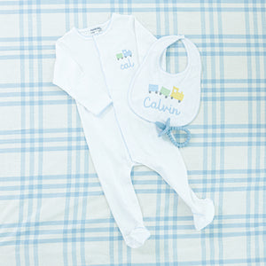 Personalized baby set featuring a white sleeper with blue train embroidery and matching bib