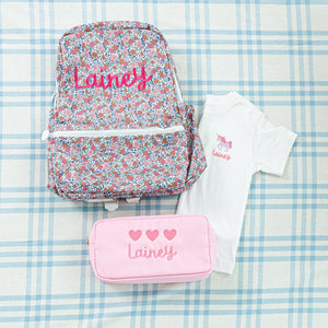 Personalized children's set featuring a floral-patterned backpack, pink pouch with hearts, and a white t-shirt