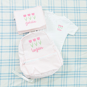 Personalized set featuring a pink striped backpack, white t-shirt with embroidered tulips and matching pouch, embroidered with tulips and names.