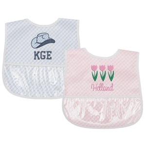 Two personalized bibs: a blue gingham bib with a cowboy hat and a pink gingham bib with tulips.